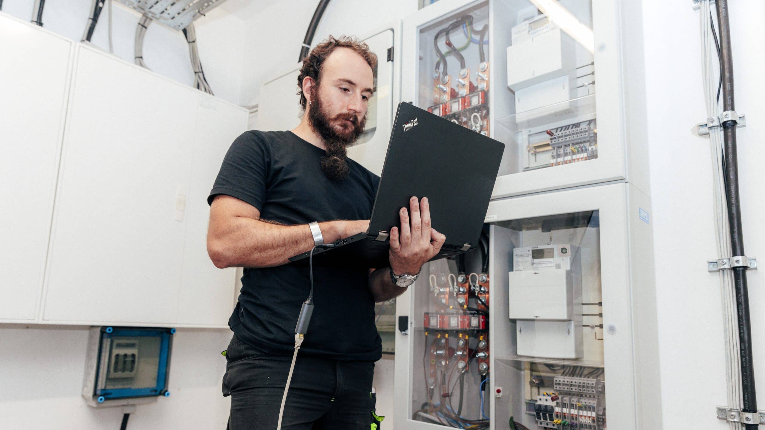 Mitarbeiter arbeitet im Rahmen der PV-Installation an Zählerkasten.